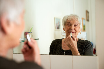 Youre never too old to play the femme fatale. Portrait of a happy senior woman applying makeup...