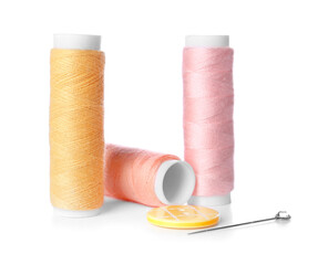 Thread spools, ball pin and button on white background