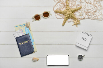 Frame made of passport, mobile phone, calendar and sunglasses on white wooden background