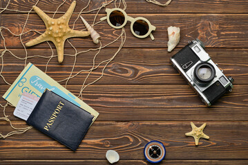 Frame made of passport, starfishes, photo camera and sunglasses on dark wooden background