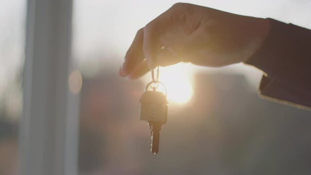 Young businessman giving key ring to a woman after purchasing the stylish modern apartment in slow-motion. Agreement done for buying a new house