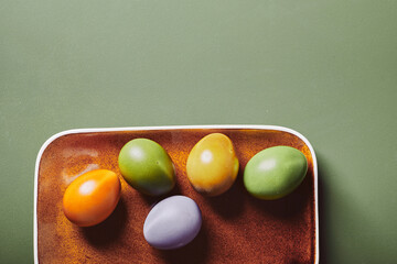 Colored with natural dye Easter eggs on brown ceramic plate. Flatlay with copy spac