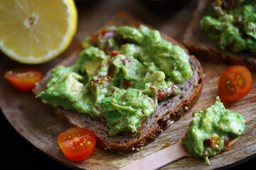 Selective focus. Macro. Guacamole toasts on a wooden board. Healthly food. Keto diet.