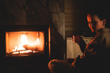 Cozy night in the cabin by the fireplace, fireplace burns in the scandinavian cottage chalet house,...