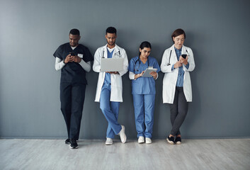 This is actually our lunch break. Shot of a group of doctors standing against a grey background at...