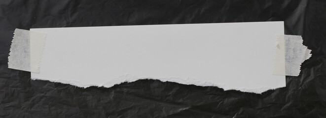 torn paper with adhesive tape, on black background, empty space for text.