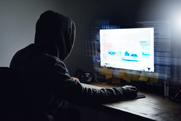 Unraveling the code. Rearview shot of a young programmer working on his computer late at night.