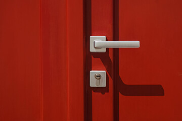 Red colored door with handle and lock close-up - obrazy, fototapety, plakaty