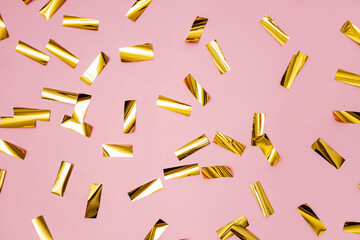 Golden shiny confetti on pink background