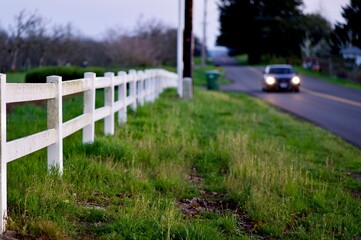 white fence along the road with car in background