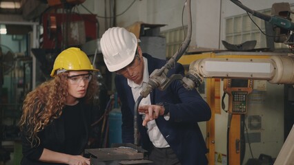 Caucasian maintenance engineer man and diverse female factory workers in hardhats talking and present or explain robot welding machine on plant, Manager supervisor and industrial manufacturing