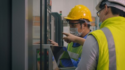 Asian factory worker man operating automated programming CNC milling control machine industry center at tool workshop manufacturing with engineer man also discuss together