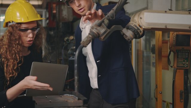 Caucasian maintenance engineer man and diverse female factory workers in hardhats talking and present or explain robot welding machine on plant, Manager supervisor and industrial manufacturing - Powered by Adobe