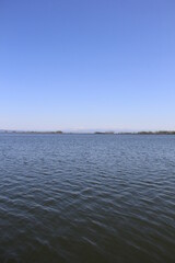 抜けるような青空と、さざ波が覆う水面、その境目の遥か彼方に雪山がうっすら見える風景