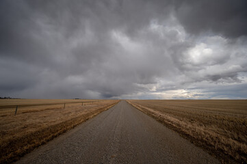 Fototapeta na wymiar Lonley prairie road leading off into the distance with living skies.