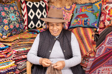 Fototapeta premium Peruvian woman weaving baby alpaca wool in a handicraft shop