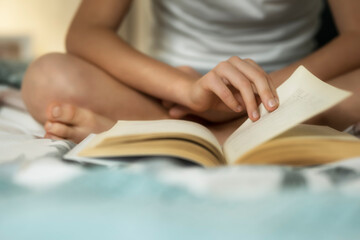 The child is reading a book. Close-up of hands and book. Selective soft focus. Home schooling.
