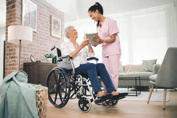 Ive captured all your big moments. Shot of a young nurse sharing information from her digital tablet with an older woman in a wheelchair.