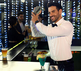 Hes a mixology master. Portrait of a barman mixing drinks behind the bar in a nightclub.