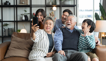 Asian big family look talk to camera and waving hand at home. video calling communicate in online chat