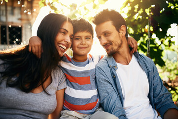 Wedged between his two favourite people in the world. Portrait of an adorable little boy bonding with his parents outdoors.
