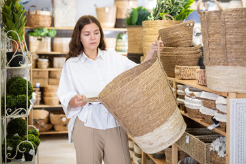 Portrait of young woman choosing storage basket at store of household goods