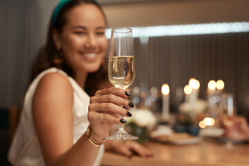 Would you like a glass. Shot of an attractive young woman sitting with her friends during a dinner party and enjoying a glass of champagne.