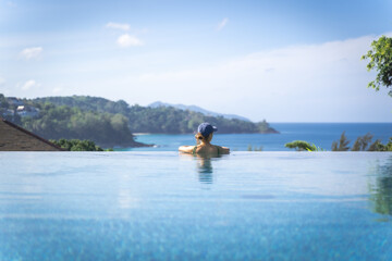 woman relaxing in the swimming pool looking the sea, Ocean in travel vacation, Phuket Thailand.