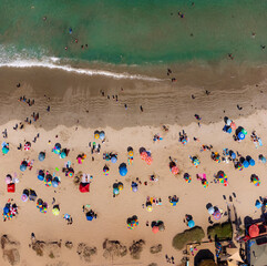 Fototapeta na wymiar Colorido paisaje en playa. Verano para disfrutar arena, sol, mar y calor. Sombrillas playeras desde drone.