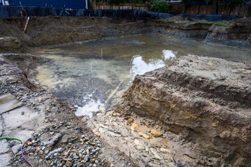 Rainwater filling the freshly dug out foundation of a new residential construction site
