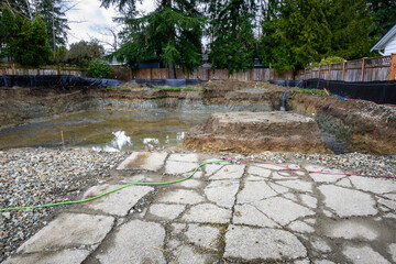 Rainwater filling the freshly dug out foundation of a new residential construction site
