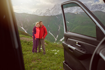 Happy couple hugs on beautiful nature mountains area out of car  - 498663030