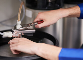 Skilled hands working on your water heating system. Cropped shot of a handyman repairing a pipe on a water heater.