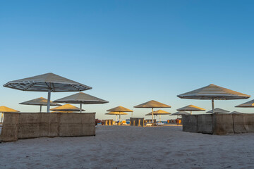 A clear morning on the Red Sea coast. Lattice sun umbrellas and wicker fences stand on the sandy beach. Blue sky. Egypt. Safaga