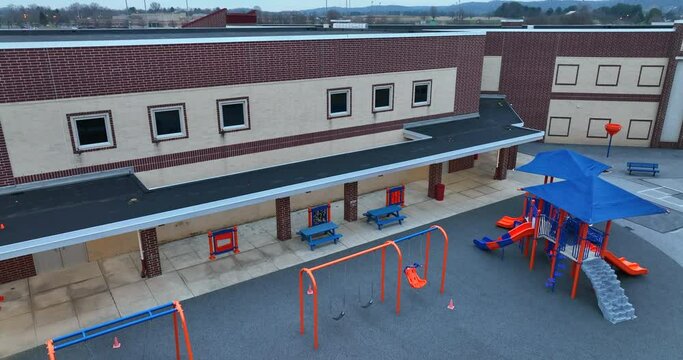 Recess playtime recess equipment at public school in America. Rising aerial reveal of campus.