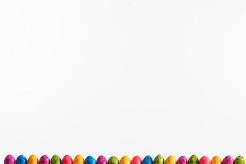 Many colorful eggs arranged in one row on a white background. Easter.