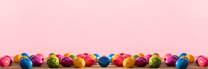 Fototapeta na wymiar In panoramic view scattered colorful hen eggs on linen fabric. Easter.