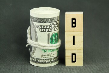 a roll of paper money and a wooden cube with the word bid