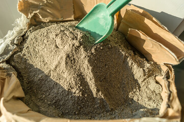 Grey sand-concrete dry mix in an open paper bag. Concrete dry powder for leveling walls and floors....
