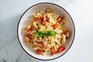 creamy vegan garlic fusilli pasta with cherry tomatoes and basil topping, healthy plant-based food