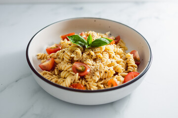 creamy vegan garlic fusilli pasta with cherry tomatoes and basil topping, healthy plant-based food