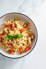 creamy vegan garlic fusilli pasta with cherry tomatoes and basil topping, healthy plant-based food