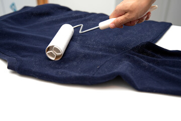 a hand removing lint from one's clothes