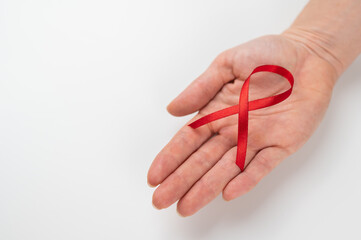 Female palm with a red ribbon on a white background. Symbol of the fight against AIDS.