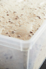Dough in a container. Bread with flax seeds. The concept of healthy whole grain bread with cereals. Vertical photo.
