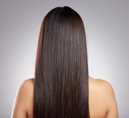 Simply sleek strands. Rearview shot of a young woman with long silky hair posing against a grey...