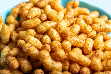 Puffed corn peanuts snacks on plate. Close-up.