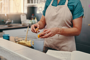 Lets get it cracking. Cropped shot of an unrecognizable woman cracking egg shells while baking inside her kitchen.