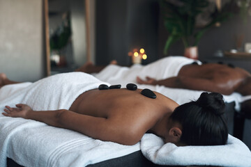 Theres no better feeling than a deep massage. Shot of a young woman getting a hot stone massage at...