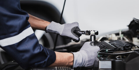 Professional mechanic working on the engine of the car in the garage. Car repair service.
